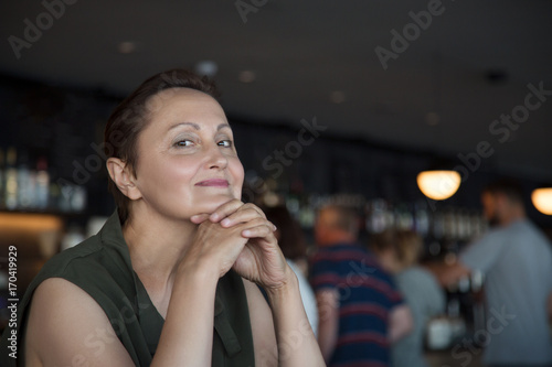 Older woman portrait. Nice picture of a middle aged elder woman in the bar. Blurred cafe/bar/pub background