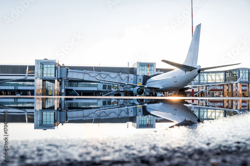 Passenger airplane parked to a air bridge with reflection in a puddle photo