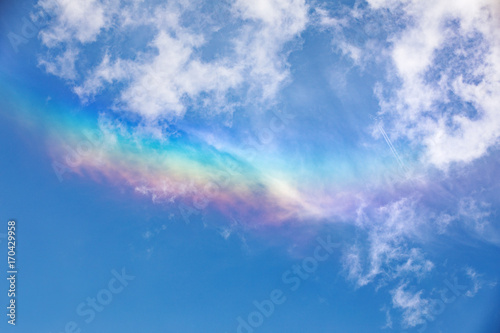 Halo against the Blue sky and nice cirrus clouds. RaInbow colors in blue sky.