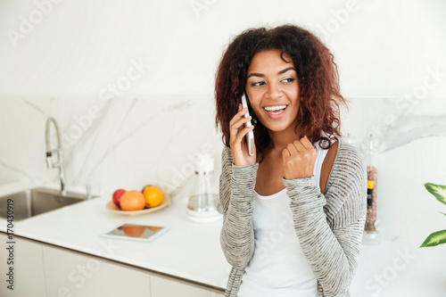 Young woman talking on phone in kitchen