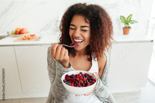 Canvas Print Young woman eating healthy food in kitchen