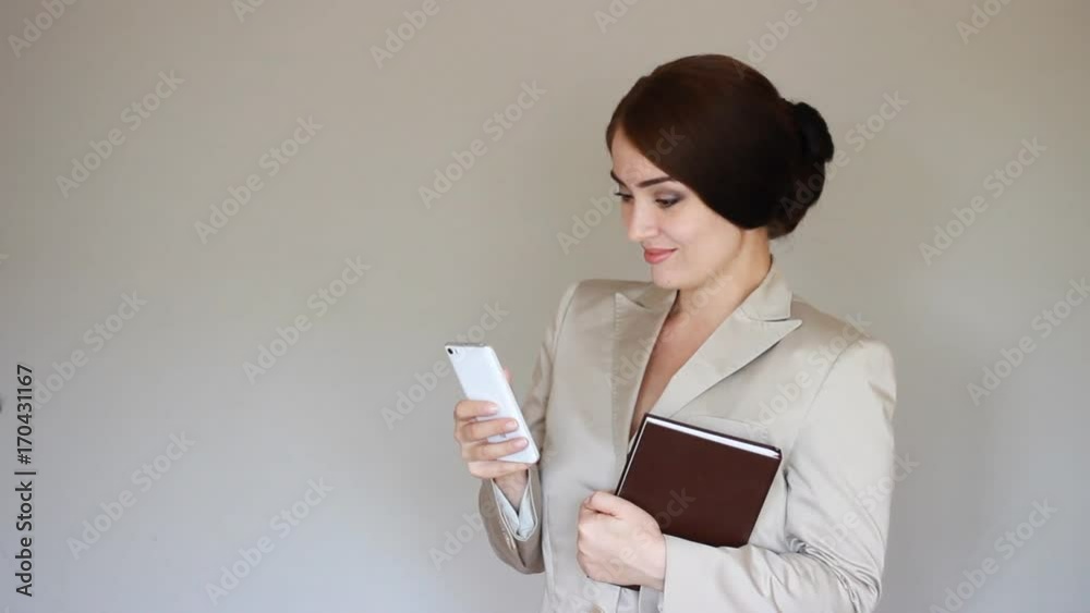 Young Elegant beautiful woman smiling and texting on smartphone. The concept of telecommunications and business Young Elegant beautiful woman smiling and texting on smartphone. The concept of telecommunications and business