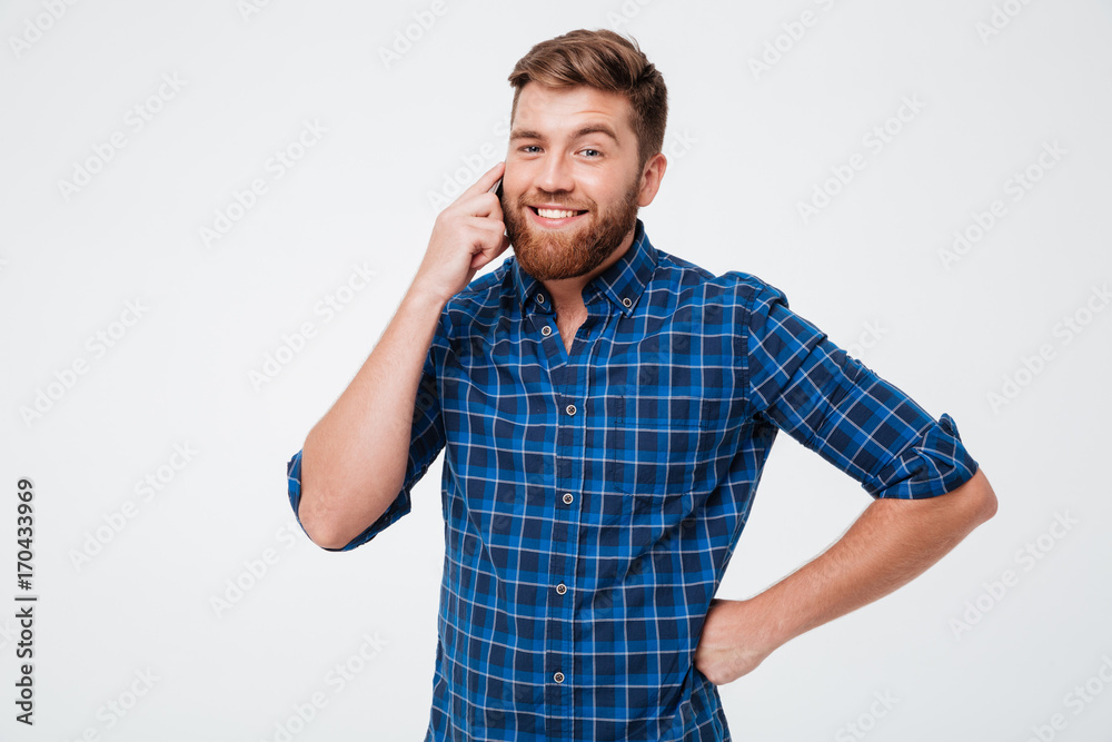 Smiling bearded man in checkered shirt talking by the smartphone Smiling bearded man in checkered shirt talking by the smartphone