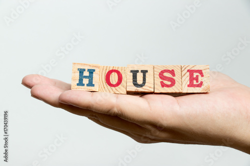 Man hold wood block with wording house on concrete background