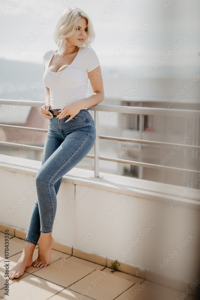 Young blonde woman sitting and relaxing at terrace on chair with city view. Fresh air in the morning of weekend or free day. Young blonde woman sitting and relaxing at terrace on chair with city view. Fresh air in the morning of weekend or free day.