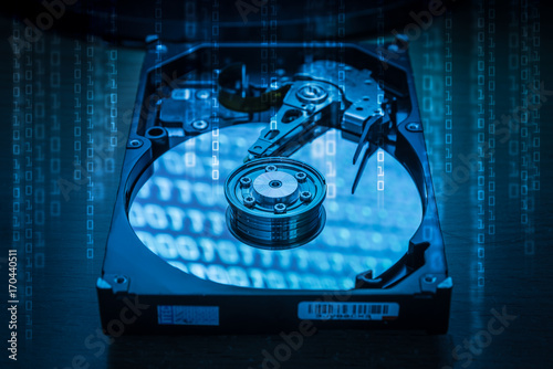 The abstract image of inside of hard disk drive and binary code hologram on top. the concept of data, hardware, and information technology.