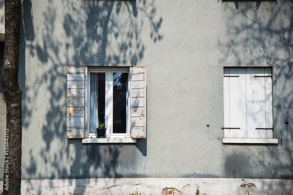 Decorative white window on an a white wooden wall in Italy