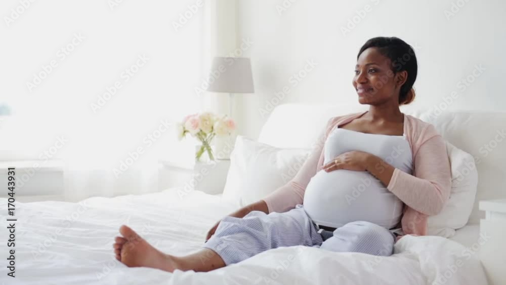 pregnant african woman watching tv in bed at home pregnant african woman watching tv in bed at home