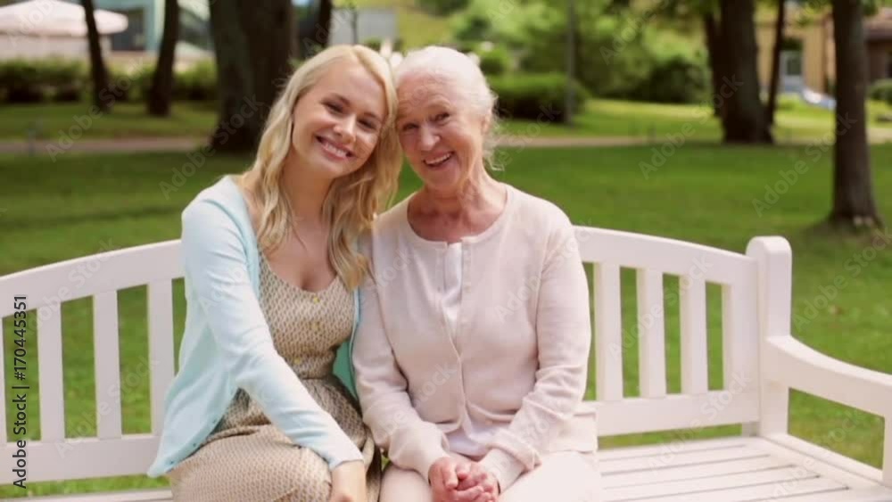 daughter with senior mother sitting on park bench daughter with senior mother sitting on park bench