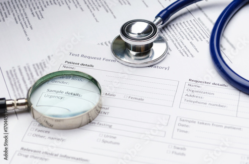 close up stethoscope  magnifying glass and patient information form on desk  heart healthcare technology  medical diagnosis  medical report record and history patient concept  selective focus