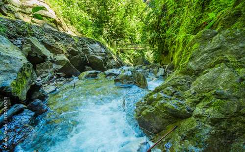 Beautiful river inside of a green forest with stones in river at Mindo