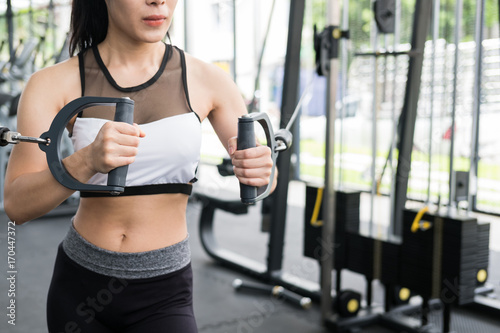 young woman execute exercise with machine in fitness center. female athlete pump up muscle with cable crossover in gym. sporty girl working out in health club.