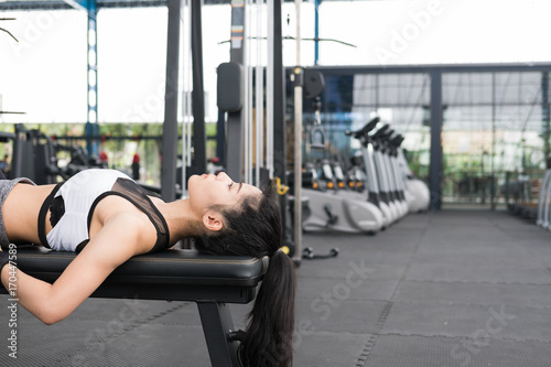 young woman in sportswear doing stretching exercise before training in fitness center. female athlete warm up her body in gym. sporty girl working out in health club.