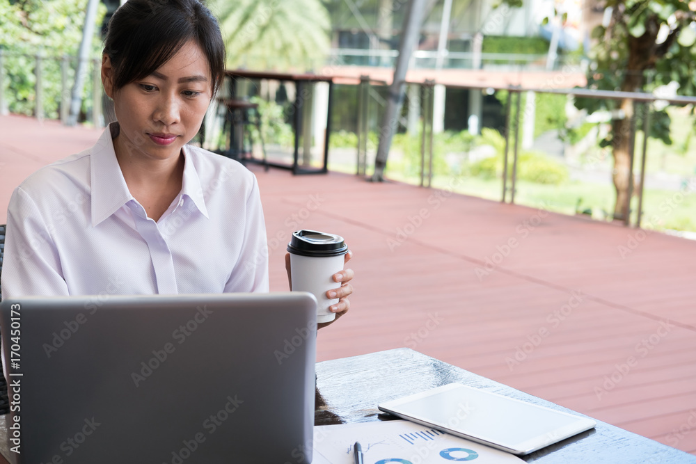businesswoman with laptop computer & financial summary graph sitting outside office building. young asian woman analyzing investment charts outdoors. business people with coffee woking online businesswoman with laptop computer & financial summary graph sitting outside office building. young asian woman analyzing investment charts outdoors. business people with coffee woking online