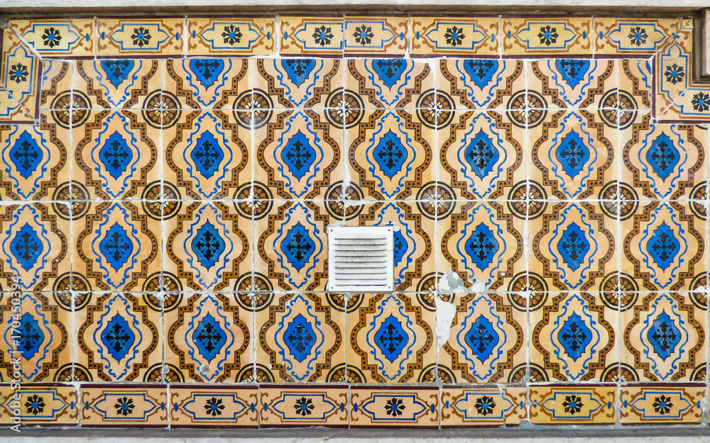 Beautiful orange and blue antique Portuguese tiles (azulejos) in Lisbon, Portugal - pattern interrupted by air vent