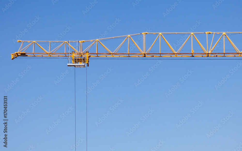 Yellow construction crane against blue sky in Lisbon, Portugal