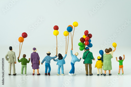 back view of miniature happy family holding balloons with white background as happy family concept. photo