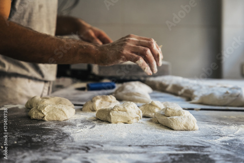 Baker preparing bread. Close up of hands kneading dough.