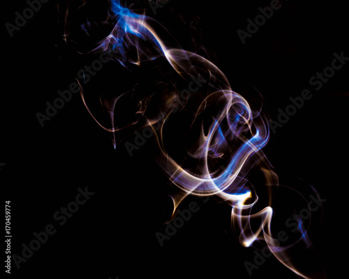 multicolored smoke dissipates in the air on an isolated black background