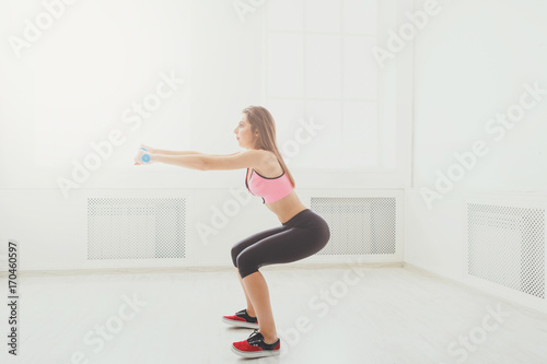 Young beautiful woman in sportswear doing squat © Prostock-studio