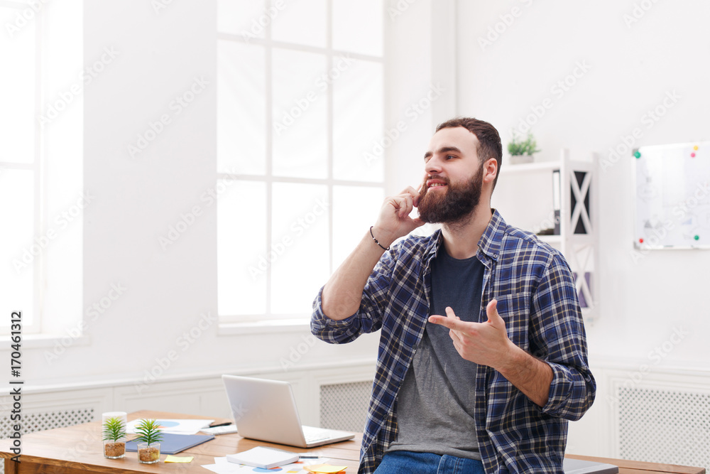 Fototapeta premium Young smiled businessman has a mobile talk in modern white office