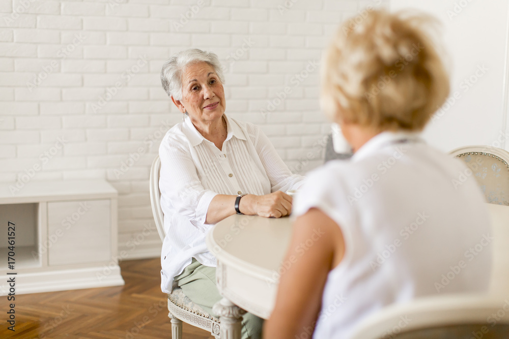 Two senior women drinking coffee at home and talking Two senior women drinking coffee at home and talking