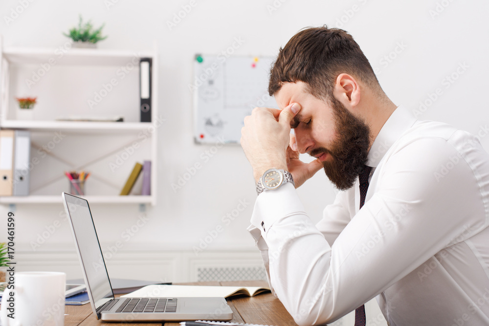 Young exhausted businessman thinking about solution in white office Young exhausted businessman thinking about solution in white office