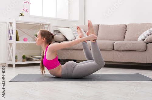 Woman training yoga in bow pose.