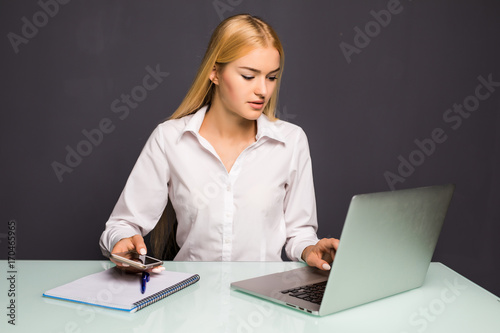 Portrait of a young business woman speak at phone and make notice in notebook at office