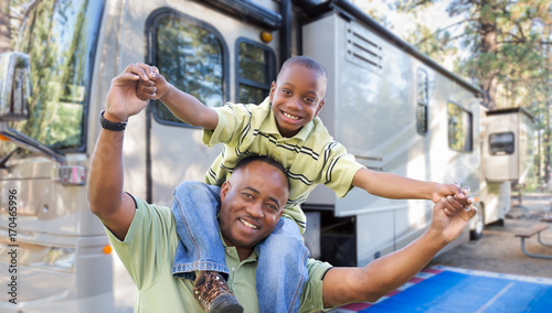 Happy African American Father and Son In Front of Their Beautiful RV At The Campground.