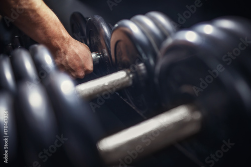 Man takes a dumbbell in the gym