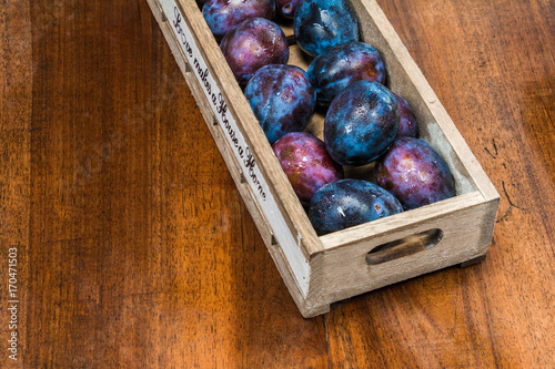 fresh plums with waterdrops on it in a wooden box