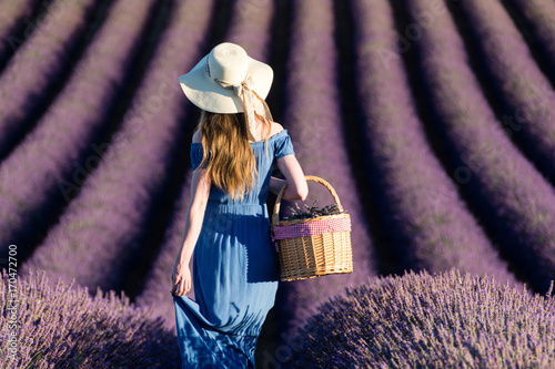 Girl in a white hat with a basket walking through lavender fields