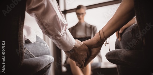 Couple holding hands with marriage counselor