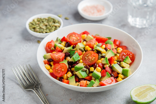Avocado  tomato  black  bean  corn and bell pepper salad in white bowl