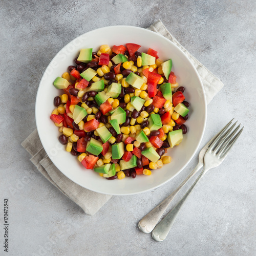 Avocado, black bean, corn and bell pepper salad in white bowl