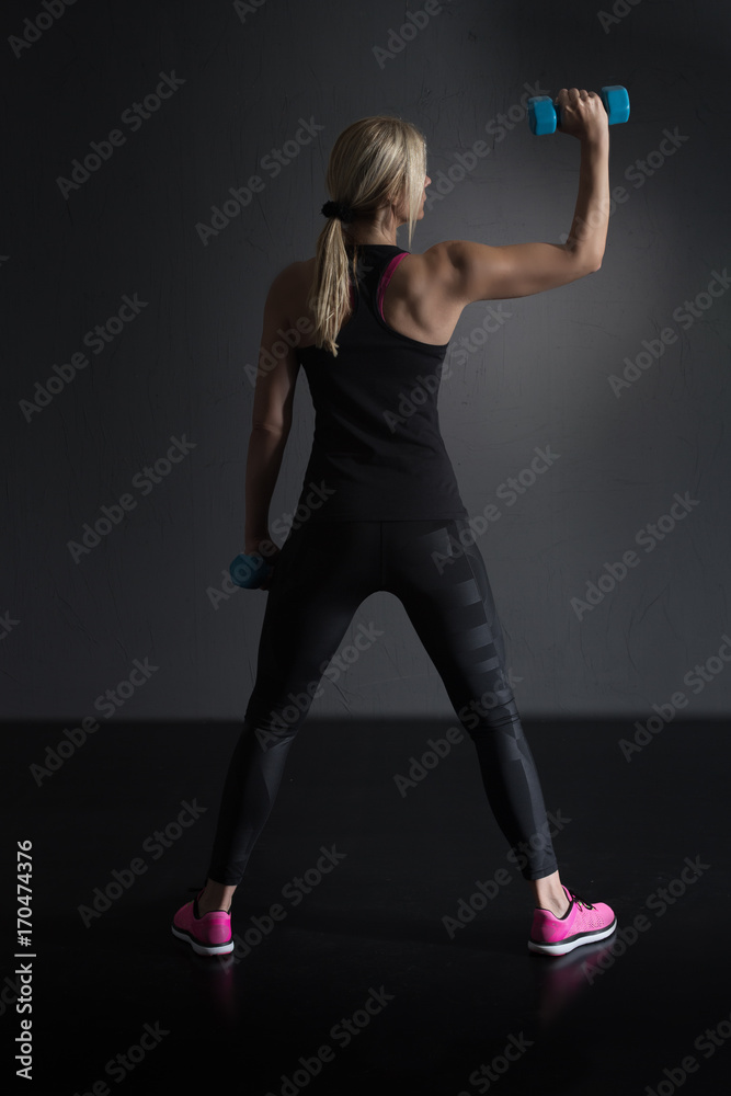Reifere Frau im schwarzen Sport Outfit macht Workout vor einem dunklen Hintergrund Reifere Frau im schwarzen Sport Outfit macht Workout vor einem dunklen Hintergrund