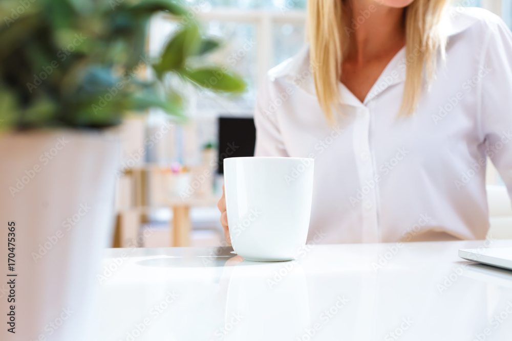 Young business woman drinking coffee in her office Young business woman drinking coffee in her office