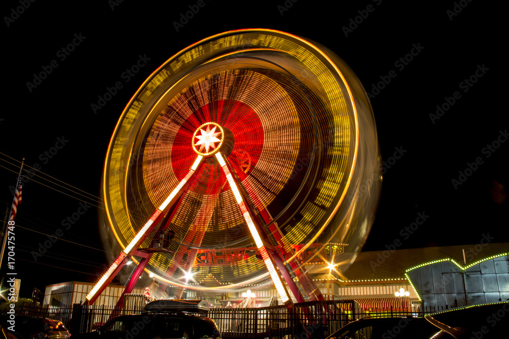 A long exposure photograph of a spinning ferris wheel against a black night sky in New Jersey, USA