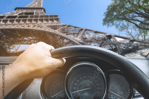 View on the dashboard of the truck driving.The driver is holding the steering wheel. Eiffel tower is in front of the car.