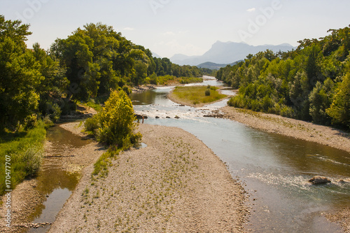 Fototapeta Naklejka Na Ścianę i Meble -  A view of the Drome River in the South East of France at the height of summer when the river is at a low and shale beaches are revealed. The alps can be seen in the distance