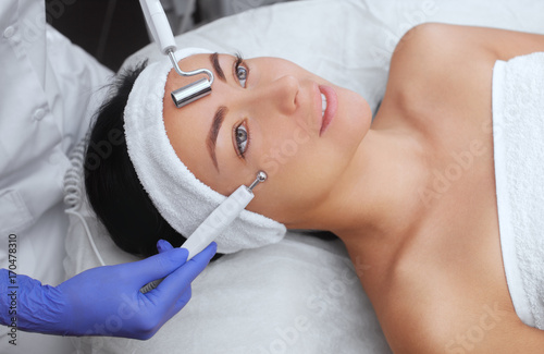 The cosmetologist makes the apparatus a procedure of Microcurrent therapy of a beautiful, young woman in a beauty salon. Cosmetology and professional skin care.