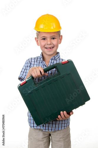 Studio picture of a young happy future builder in a beautiful blue checkred shirt and yellow helmet, holding toolbox photo