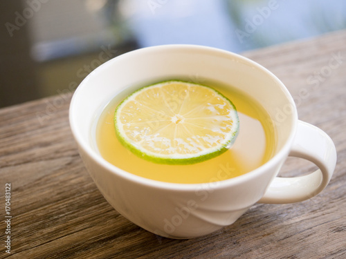 Hot honey lemon tea in white mug on wood table.