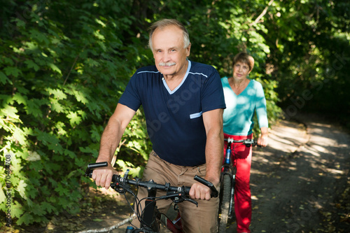 happy senior couple ride on bicycle in the park