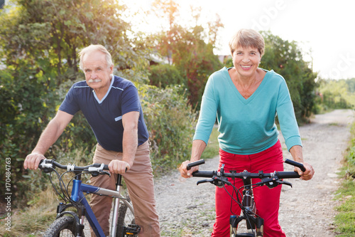 happy senior couple ride on bicycle in the park