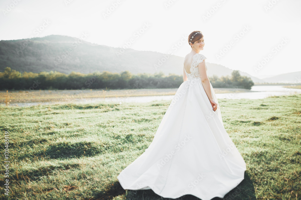 Beauty woman, bride with perfect white dress posing on the rock background mountains