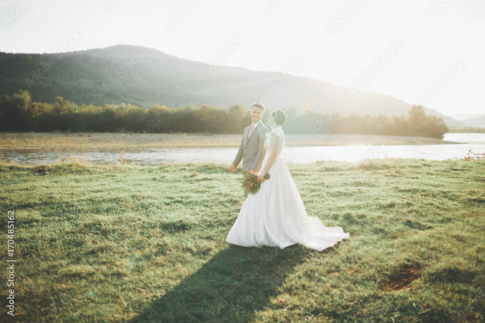 Newly married couple running and jumping in park while holding hands Newly married couple running and jumping in park while holding hands