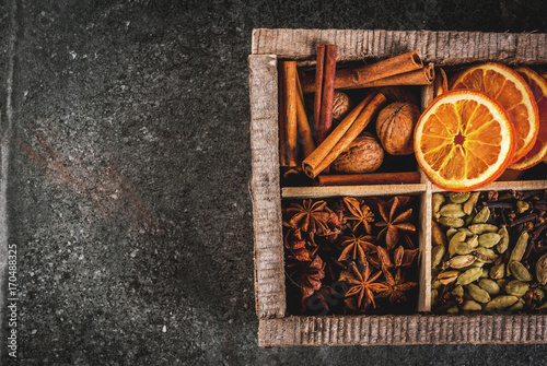 Christmas spices for baking, cocktails, mulled wine, with gingerbread cookies (stars) - dried apple, orange, cardamom, cloves, cinnamon, anise.  old wooden box, black stone table. copy space top view © ricka_kinamoto