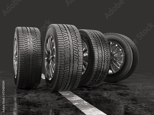 Four car tires rolling on a road on a gray background.